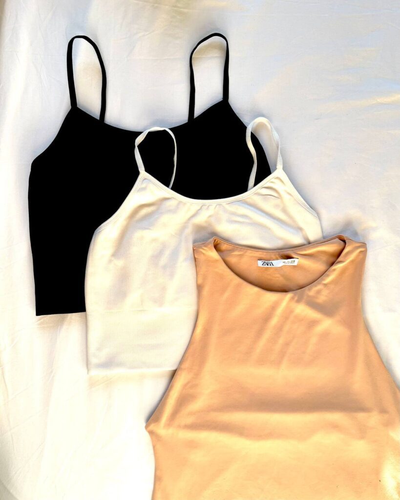 three vest tops laid out on a bed