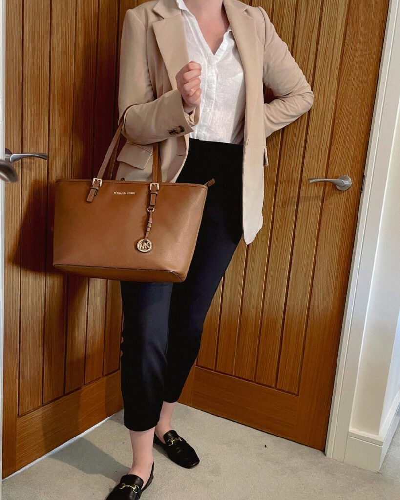 a girl wearing a nude blazer and a white shirt and black trousers